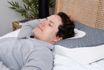 A man is peacefully sleeping on an Elviros pillow, his head comfortably cradled by the pillow's ergonomic design.