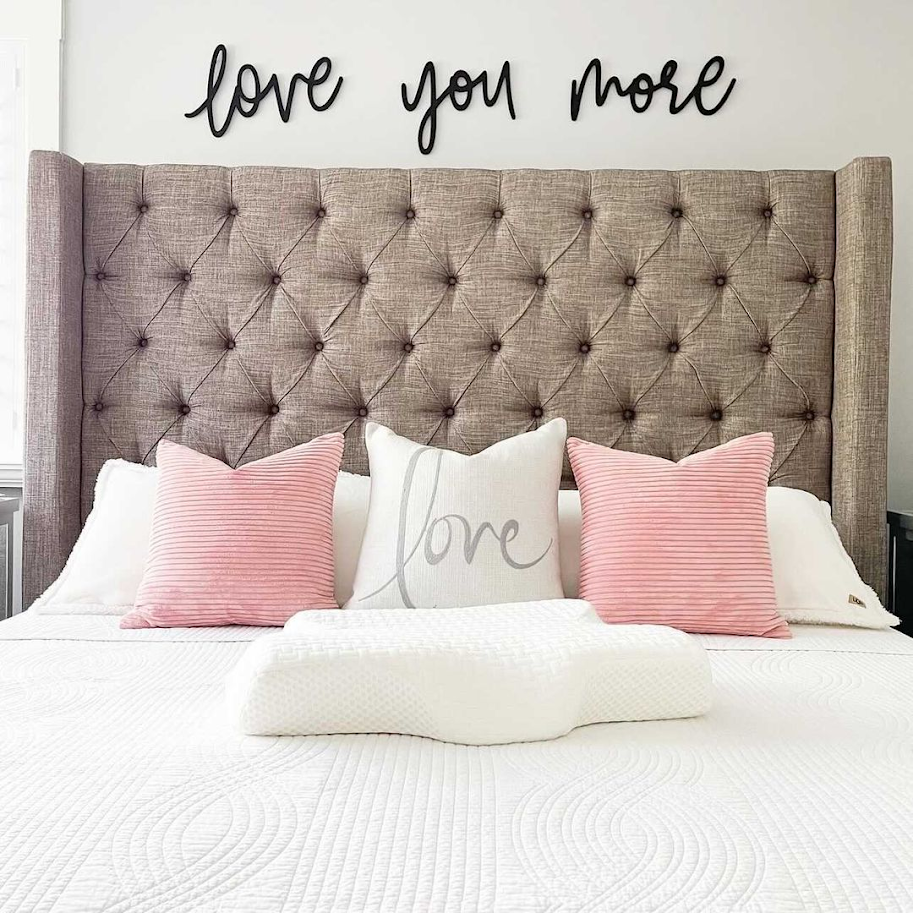 Elviros Contour Pillow on bed with 2 pink pillows