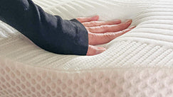 A person's hand pressing down on Elviros memory foam mattress