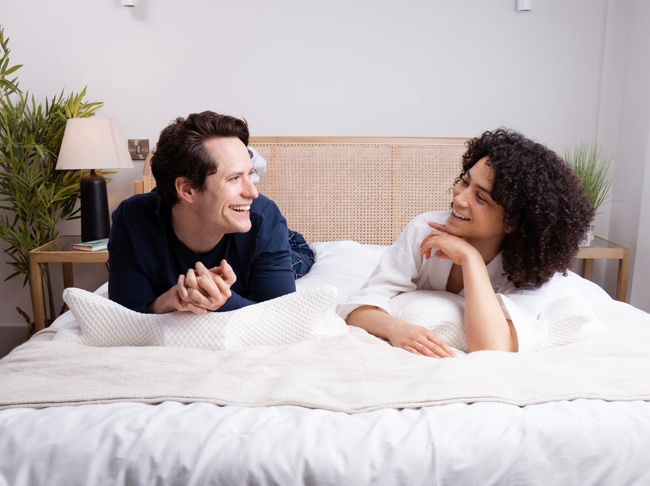 Two people are lying on an Elviros mattress, comfortably chatting with each other.