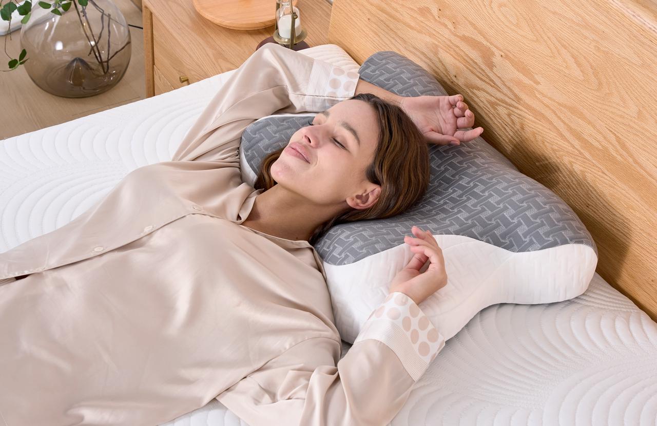 A back sleeper rests peacefully on a memory foam pillow, with their head cradled gently by the pillow's contoured shape.